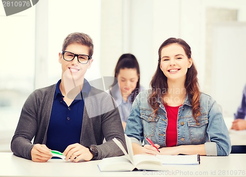 Image of two teenagers with notebooks and book at school