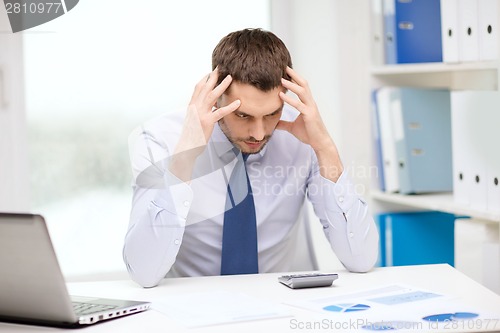 Image of stressed businessman with laptop and documents