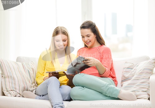 Image of two girlfriends reading magazine at home