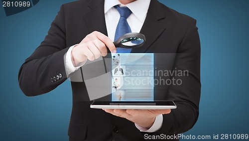 Image of businessman hand holding magnifier over tablet pc