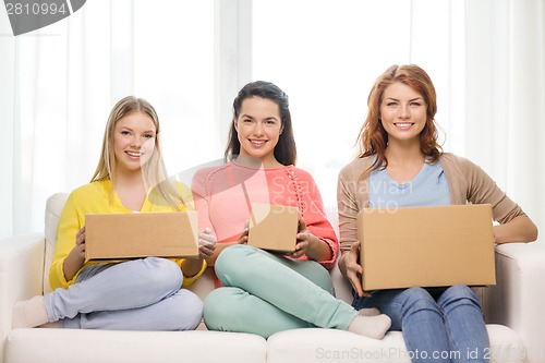 Image of smiling teenage girls with cardboard boxes at home