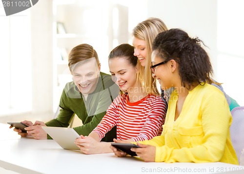 Image of smiling students looking at tablet pc at school