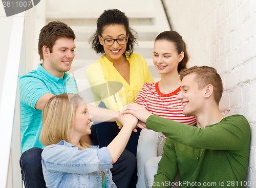 Image of smiling students with hands on top of each other