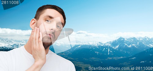 Image of beautiful calm man touching his face