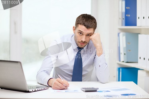 Image of stressed businessman with laptop and documents