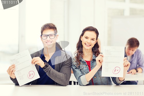 Image of two teenagers holding test or exam with grade A
