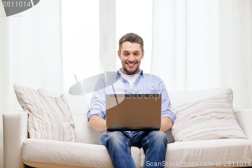 Image of smiling man working with laptop at home