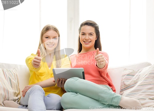 Image of two smiling teenage girls with tablet pc at home