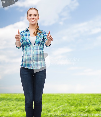 Image of young woman in casual clothes showing thumbs up