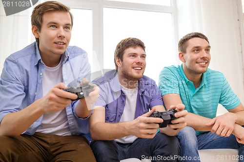 Image of smiling friends playing video games at home