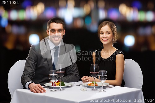 Image of smiling couple eating main course at restaurant