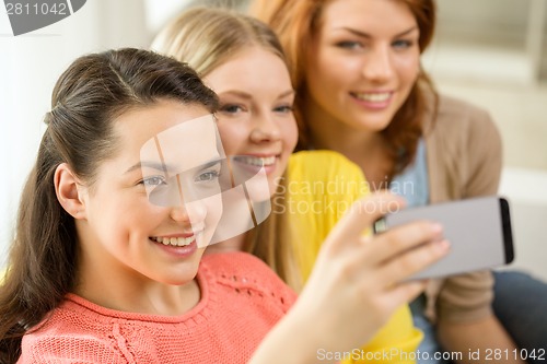 Image of smiling teenage girls with smartphone at home