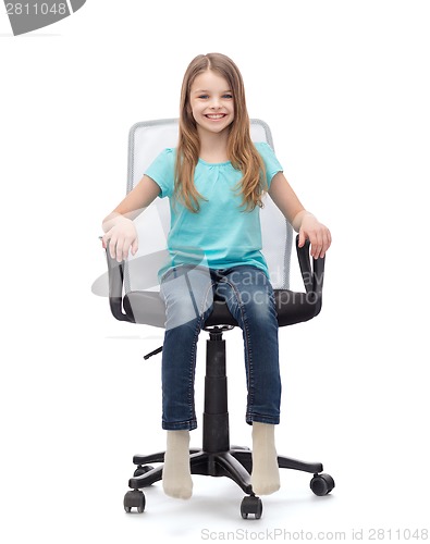 Image of smiling little girl sitting in big office chair
