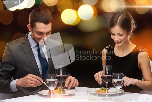 Image of smiling couple eating main course at restaurant