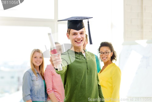 Image of smiling male student with diploma and corner-cap