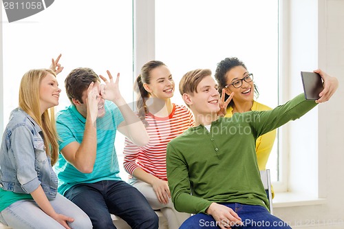 Image of smiling students making picture with tablet pc