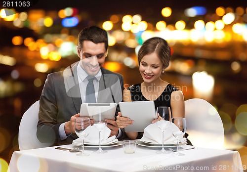 Image of couple with menus on tablet pc at restaurant