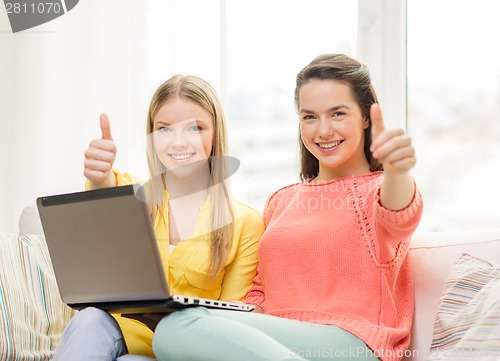 Image of two smiling teenage girls with laptop at home