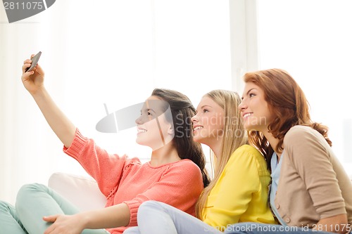 Image of smiling teenage girls with smartphone at home