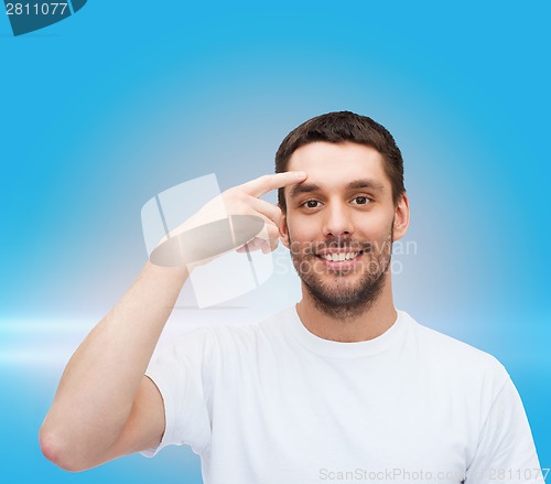 Image of smiling young handsome man pointing to forehead