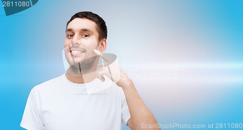 Image of smiling young handsome man pointing to cheek