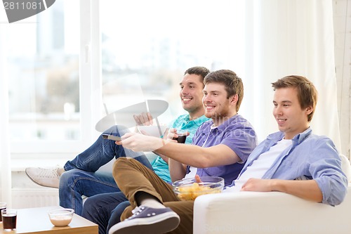Image of smiling friends with remote control at home