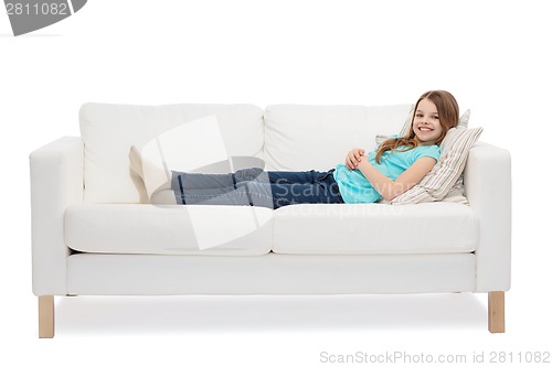 Image of smiling little girl lying on sofa