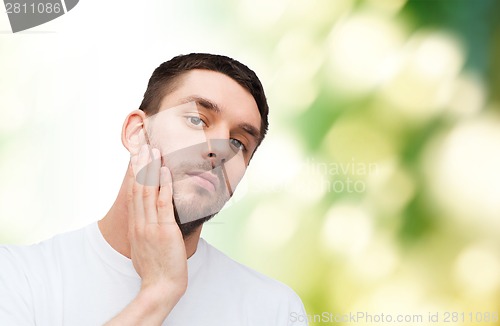 Image of beautiful calm man touching his face