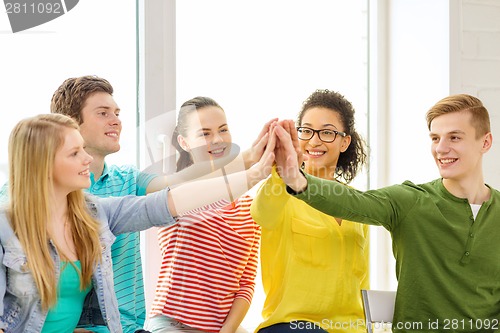 Image of smiling students making high five gesture sitting