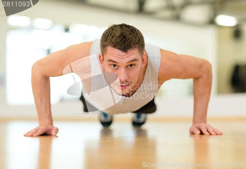 Image of concentrated man doing push-ups in the gym