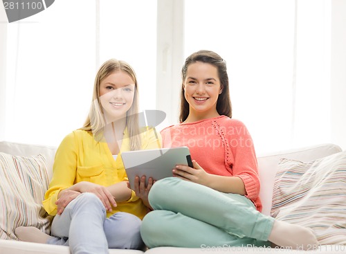 Image of two smiling teenage girls with tablet pc at home