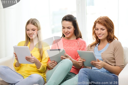 Image of three smiling teenage girls with tablet pc at home