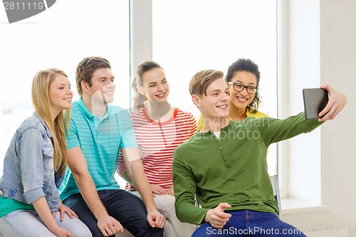 Image of smiling students making picture with tablet pc