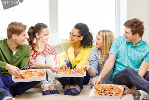 Image of five smiling teenagers eating pizza at home