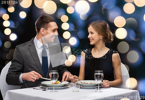 Image of smiling couple eating main course at restaurant