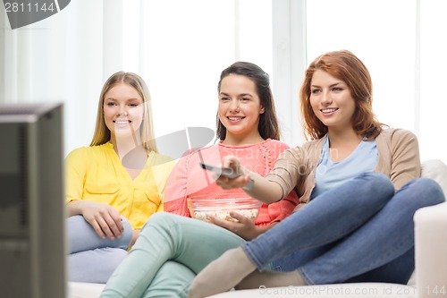 Image of three smiling teenage girl watching tv at home