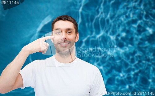 Image of smiling young handsome man pointing to eyes