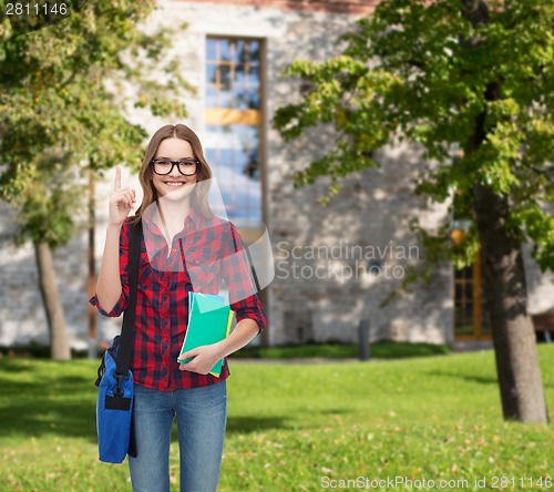 Image of smiling female student with bag and notebooks