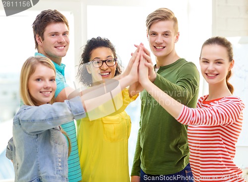 Image of five smiling students giving high five at school