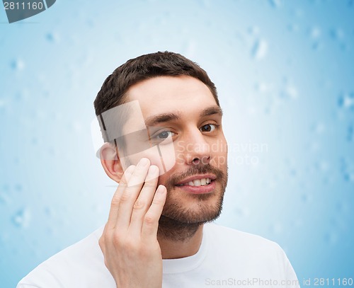 Image of beautiful smiling man touching his face