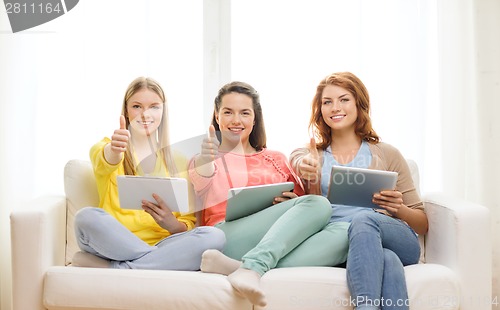 Image of three smiling teenage girls with tablet pc at home