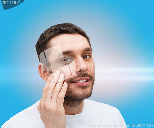 Image of beautiful smiling man touching his face