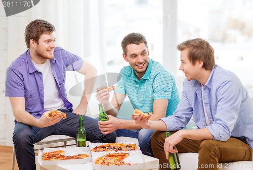 Image of smiling friends with beer and pizza hanging out