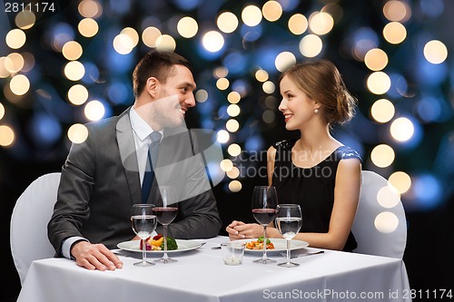 Image of smiling couple eating main course at restaurant