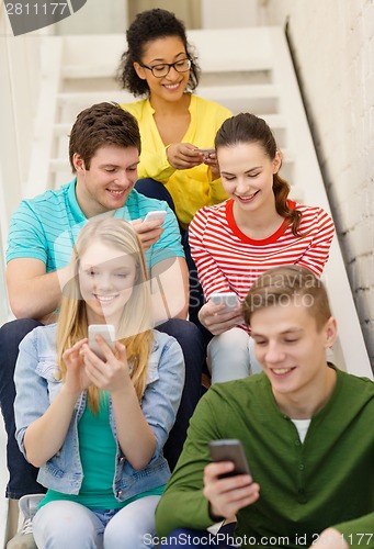 Image of smiling students with smartphone texting at school