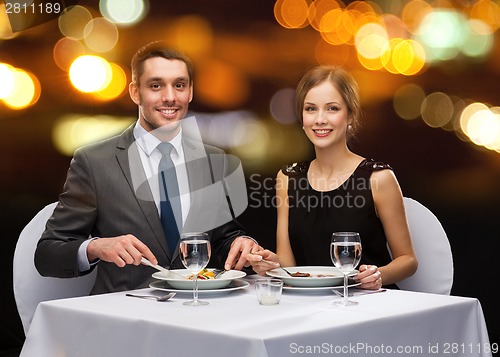 Image of smiling couple eating main course at restaurant