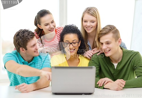 Image of smiling students looking at laptop at school