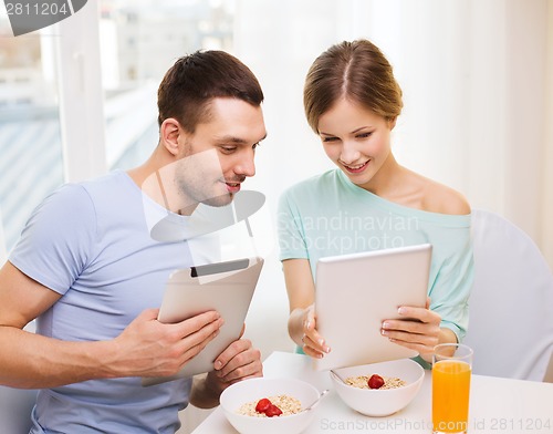 Image of smiling couple with tablet pc reading news