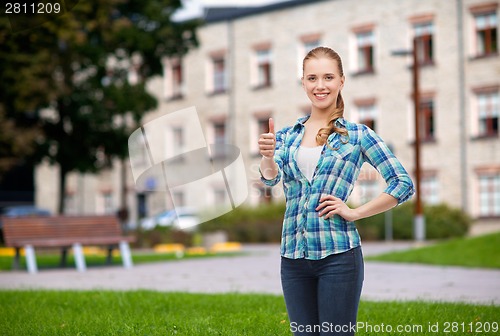 Image of young woman in casual clothes showing thumbs up