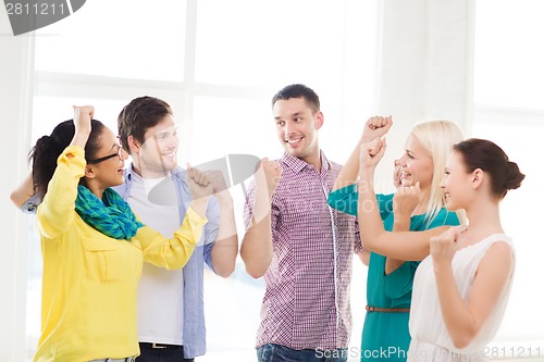 Image of happy creative team celebrating victory in office